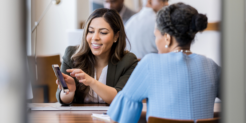 Global Payments – Ladies at table with phone Two ladies sat at table - Global Payments and future commerce