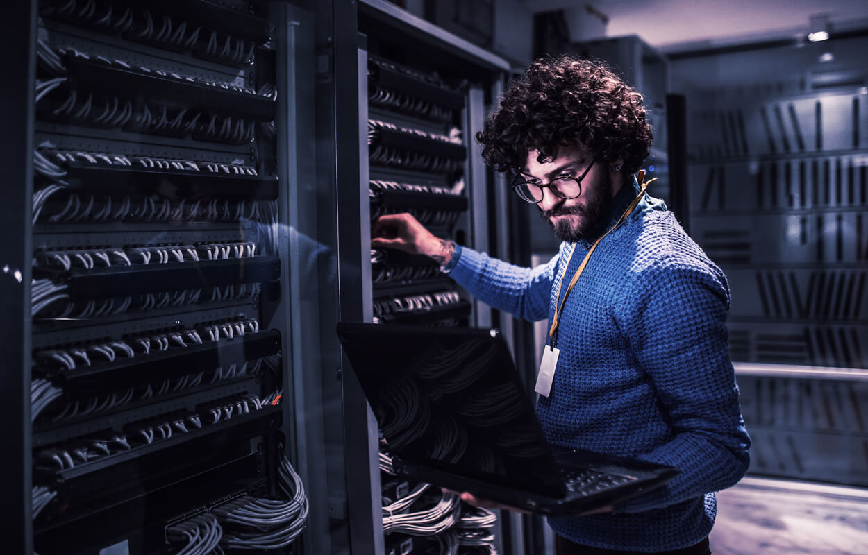 Man stood at server with laptop – MLP Man stood at server with laptop - AI in the insurance industry