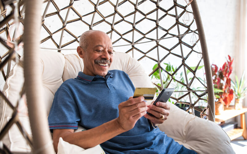 Man in chair reading credit card - Client Self-Service